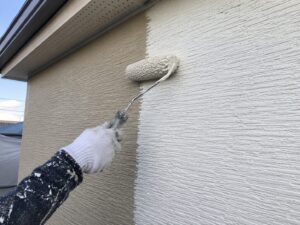 外壁をローラーで丁寧に塗装している作業イメージ
